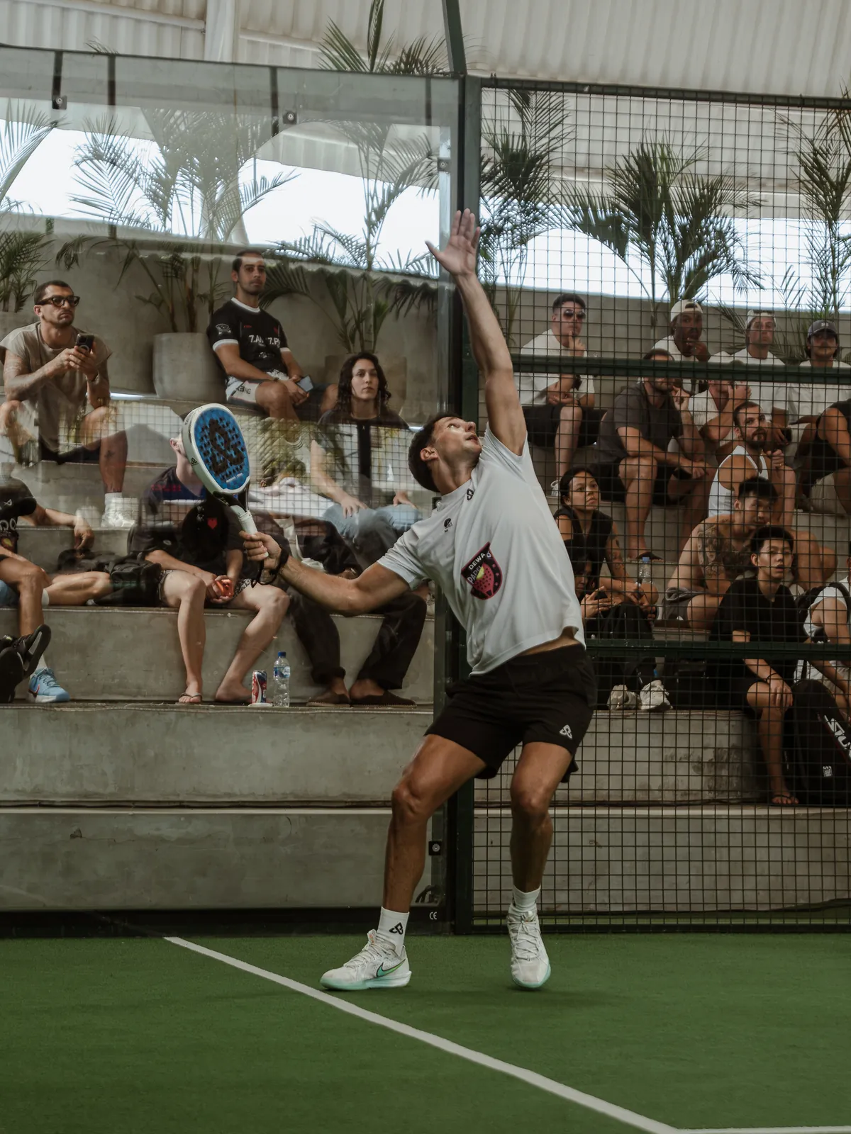 A padel player in action in front of spectators