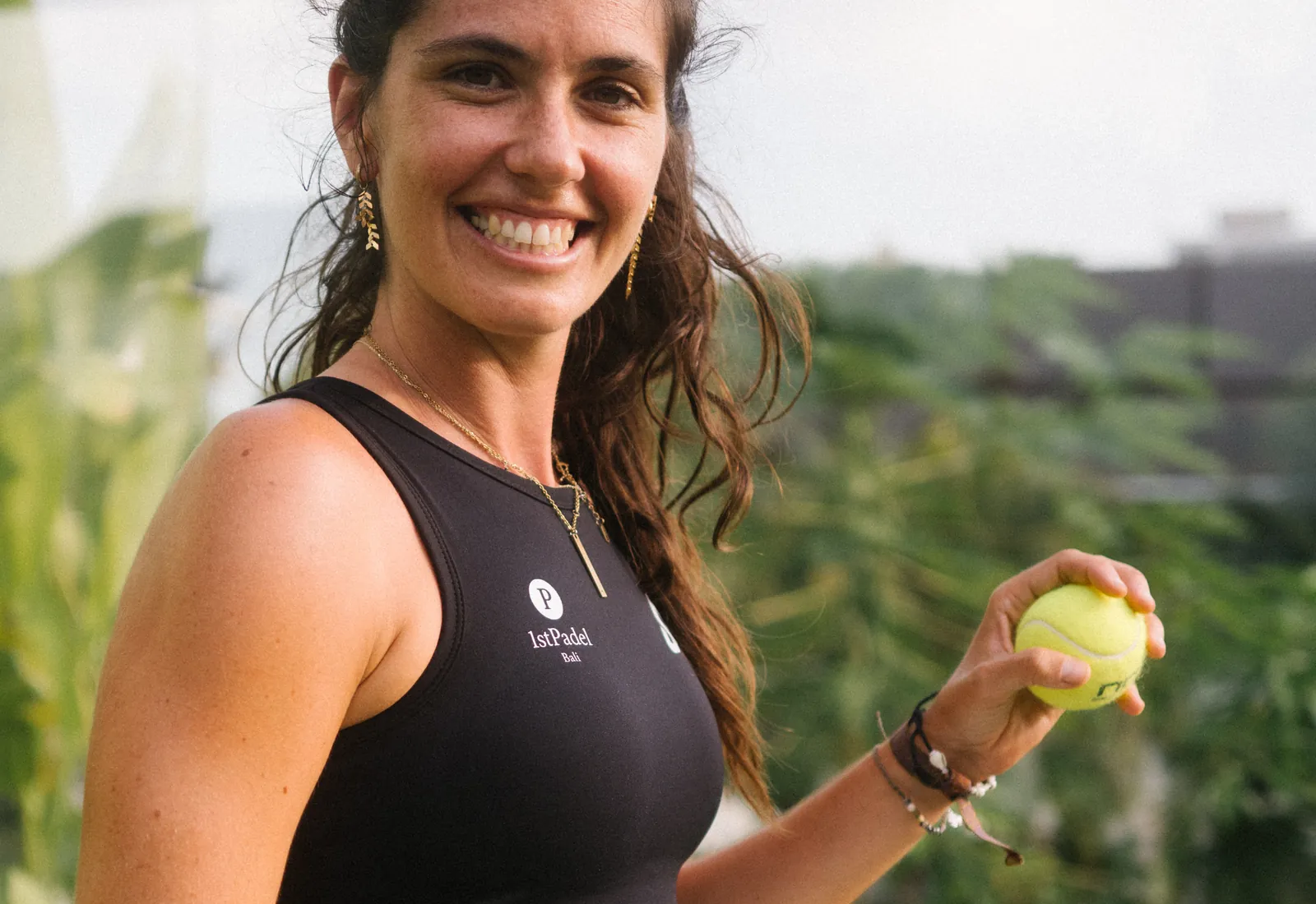 A smiling player holding a padel ball